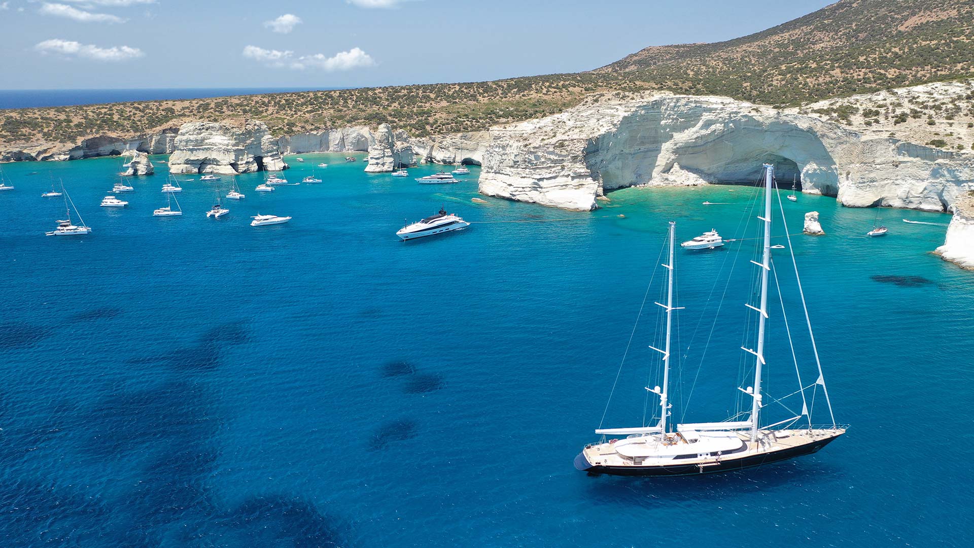 Milos boat tours sailing near Kleftiko caves with white volcanic cliffs