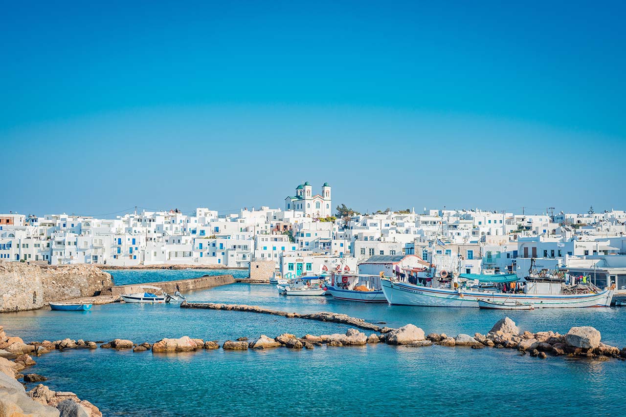 Coastal town and small harbor on Paros island with white houses by the sea
