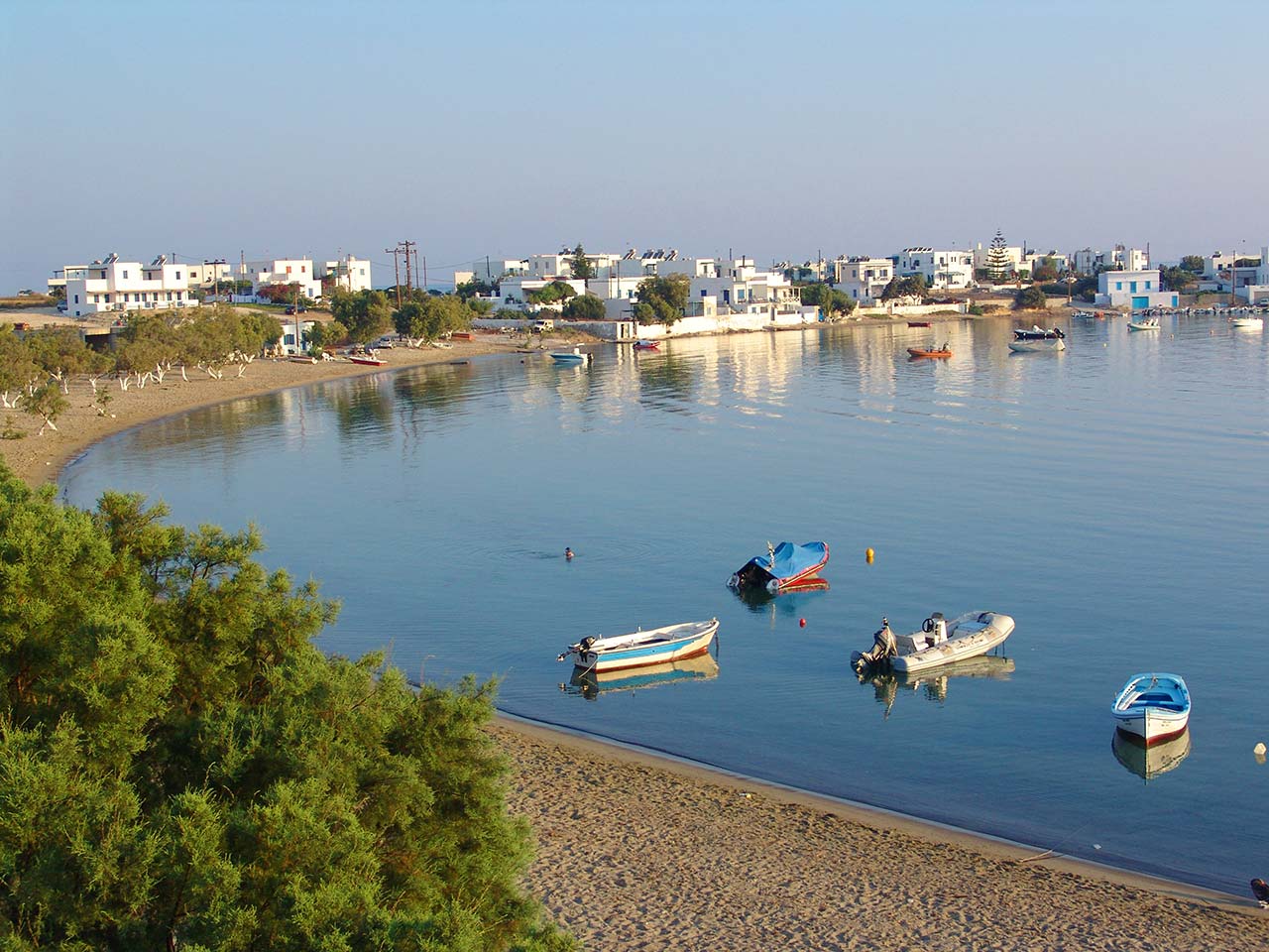 Pollonia Beach in Milos with calm shallow water and small boats along the shore