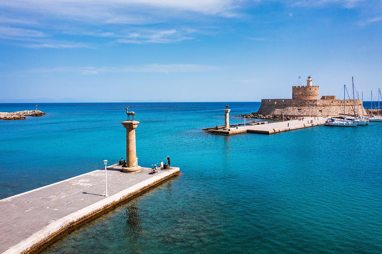Mandraki Harbor with deer statues and Fort Saint Nicholas in Rhodes Greece