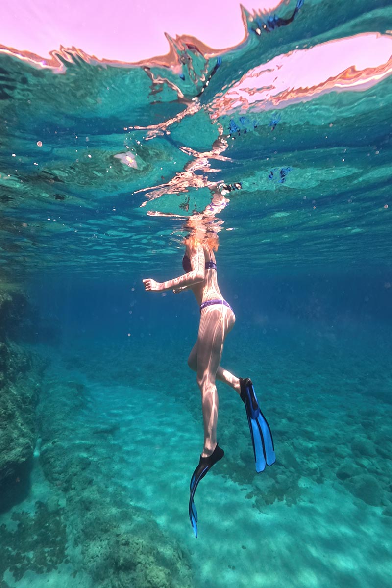 Woman snorkeling in clear emerald water near Kleftiko Milos